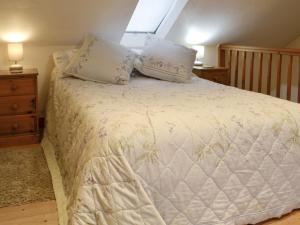 a bedroom with a white bed with pillows and a window at The Cow Shed in Llanfair-ar-y-bryn
