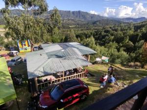 a red car parked in front of a building with a roof at Glamping Tausavita Ubaté Cundinamarca in El Bujío