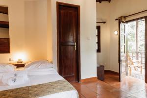 聖多美的住宿－Roça Vale dos Prazeres，一间卧室设有一张床和一个滑动玻璃门