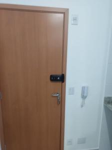 eine Holztür mit schwarzem Griff in einem Zimmer in der Unterkunft Apto a 300 metros da Canção Nova. Condomínio da Fé in Cachoeira Paulista