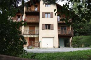 une vue extérieure d'un bâtiment avec un garage blanc dans l'établissement Agréable appartement au calme avec vue montagne, commune de Le Monêtier les Bains - Le Freyssinet, à Les Guibertes