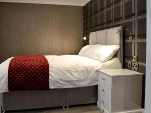 1 dormitorio con 1 cama con manta roja y mesita de noche en Fernhill Cottage, en Oxenhope