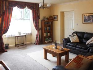 Sala de estar con sofá de cuero negro y mesa de centro en Caxton Nook, en Windermere