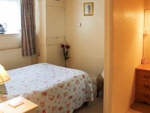 Un pequeño dormitorio con una cama y un jarrón de flores en Caxton Nook, en Windermere