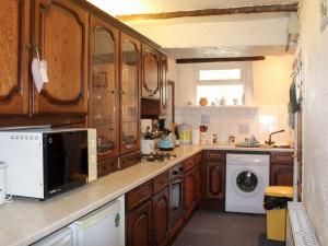 cocina con armarios de madera, lavadora y secadora en Caxton Nook, en Windermere