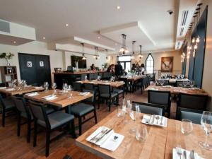 a restaurant with wooden tables and chairs and people in the background at *Nouveauté* Foyer au bois, Plage, Montagne et + in Magog-Orford