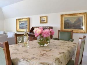 une table avec un vase de fleurs roses sur elle dans l'établissement The Garden Suite, à Oathlaw