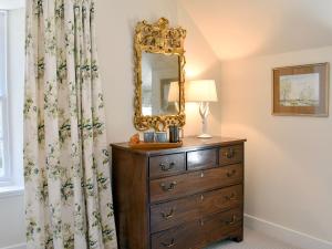 a bedroom with a dresser and a mirror on a dresser at The Garden Suite in Oathlaw
