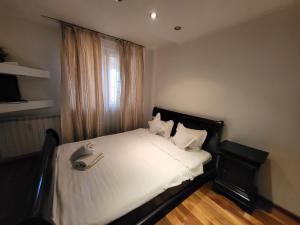 1 dormitorio con 1 cama con sábanas blancas y ventana en Baba Novac Apartment, en Bucarest