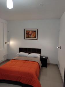 een slaapkamer met een bed met een oranje deken bij HOTEL PUNTA PARIÑAS-TALARA-PERU in Talara