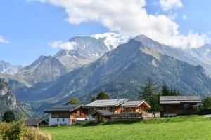 a house in a field with mountains in the background at Vielyterra - Chalet haut de gamme - Domaine du mont blanc in Saint-Gervais-les-Bains