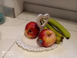 two apples and bananas on a plate with a pair of scissors at Appartamento DeLuxe con parcheggio gratuito in Segrate