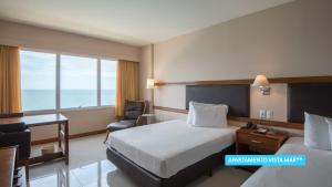 a hotel room with a bed and a desk and a chair at Vila Galé Salvador in Salvador