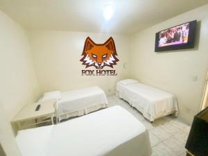 a room with two beds and a fox hotel sign on the wall at Fox Hotel Montes Claros in Montes Claros