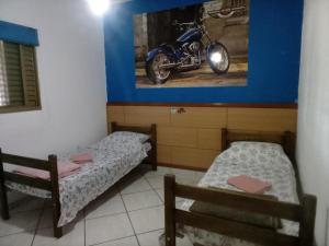 2 Betten in einem Zimmer mit einem Motorrad an der Wand in der Unterkunft RECANTO DO ALVORADA in Dourados