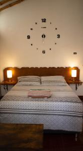 1 dormitorio con 1 cama con reloj en la pared en Lunawasi Hospedaje, en Lunahuaná