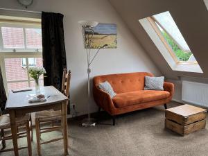 uma sala de estar com um sofá laranja e uma mesa em Gastenverblijf Neeltje em Oostkapelle