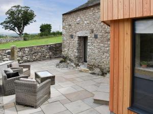 a patio with chairs and a stone wall at The Bothy in Beetham