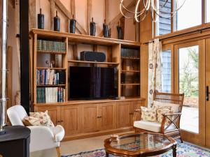 a living room with a large entertainment center with a tv at Ivy Todd Barn in Ashdon