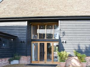 a black house with glass doors on it at Ivy Todd Barn in Ashdon
