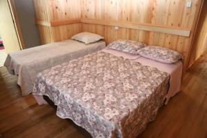 two beds in a room with wooden walls and wood floors at Casarão Biazolli in Farroupilha
