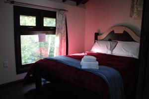 a bedroom with a red bed with a window at Pousada Laura e Emílio in Osório