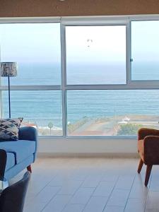 una sala de estar con una gran ventana con vistas al océano. en Stylish New Apartment with stunning Ocean View near Miraflores, en Lima