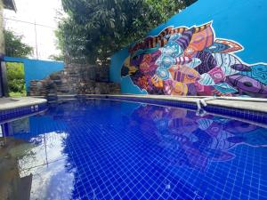 una piscina con un mural en el lateral de un edificio en Wandering Monkey Guesthouse, en Mazatlán