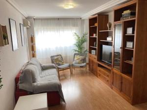 ein Wohnzimmer mit 2 Stühlen und einem TV in der Unterkunft Apartamento grande, 2 dormitorios, garaje gratis in Madrid