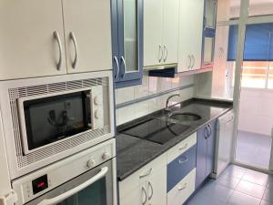 a white kitchen with a microwave and a sink at Apartamento grande, 2 dormitorios, garaje gratis in Madrid