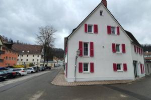 a white house with red shuttered windows on a street at Apartment Steinwald in Oberndorf in Oberndorf