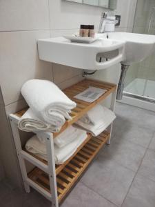 a bathroom with a sink and a shelf with towels at 215 addaura luxury room in Palermo