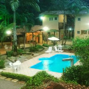 una piscina con sedie e tavolo e una casa di Pousada Recanto dos Tangaras a Juquei