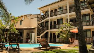 a resort with a swimming pool and chairs and a building at Pousada Stella Tropical in Salvador