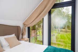 a bedroom with a bed and a large window at Słowińskie Tarasy in Smołdziński Las +72 photos