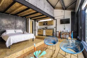 a bedroom with a bed and two chairs and a kitchen at Santa Teresita Loft in Cali