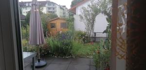 a patio with an umbrella and a garden with flowers at Cosy Room in Puchheim