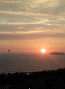 a bird flying over the ocean at sunset at Stylish New Apartment with stunning Ocean View near Miraflores in Lima