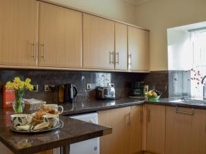 a kitchen with wooden cabinets and a plate of food on a counter at Horsemill - Uk10794 in Ballingry