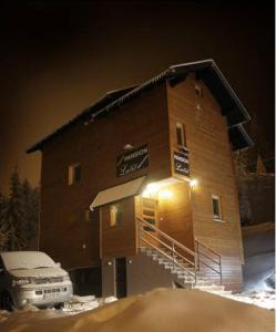 a building with a car parked in front of it at Guesthouse Lucic in Jahorina