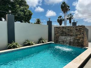 a swimming pool in a backyard with a stone wall at Aruba Bliss Condos in Oranjestad