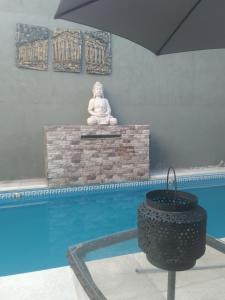 uma estátua de Buda sentada ao lado de uma piscina em Apart hotel protomy em Villa Luzuriaga