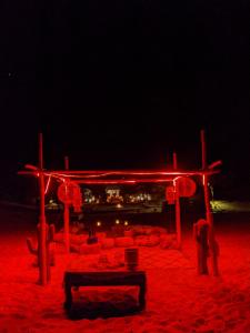 Sahara Majestic Luxury Camp في مرزوقة: بنية مضاءة حمراء على الشاطئ في الليل