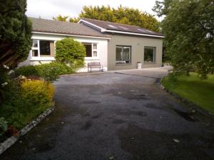 a house with a bench in front of a driveway at Spacious Contemporary Chalet type Apartment. in Galway