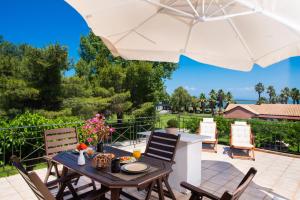 un patio con mesa, sillas y sombrilla en Villagio, en Lefkada