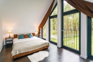 a bedroom with a large bed and large windows at Słowińskie Tarasy in Smołdziński Las