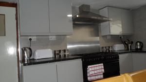 uma cozinha com armários brancos e um forno com placa de fogão em Bubblesbnb 7 Bedroom House, 16 beds, sleeps 22 em Londres