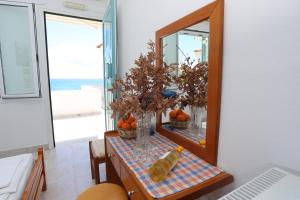 a table with a mirror and vases with oranges on it at Akrogiali Hotel in Plomarion