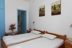 two beds in a room with white walls at Akrogiali Hotel in Plomarion