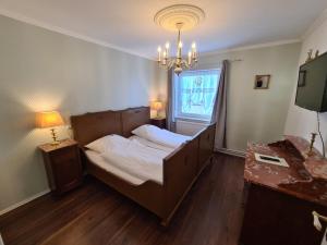 Schlafzimmer mit einem Bett, einem Fenster und einem Kronleuchter in der Unterkunft Überfahrt vor Sylt in Klanxbüll